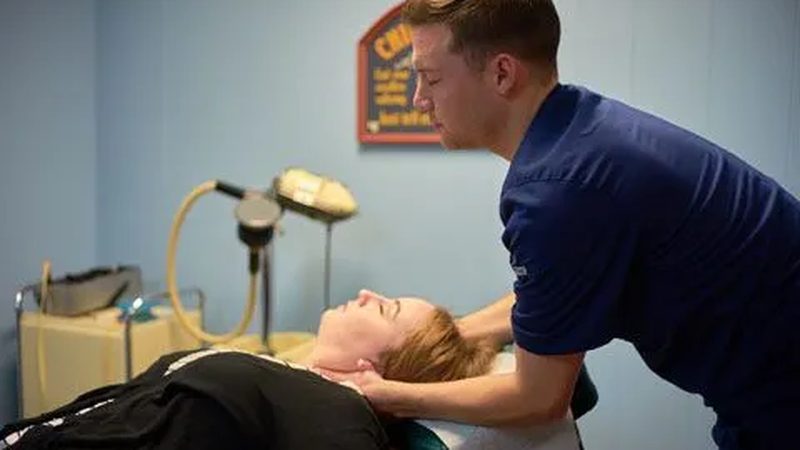 A chiropractor performing a neck adjustment on a patient
