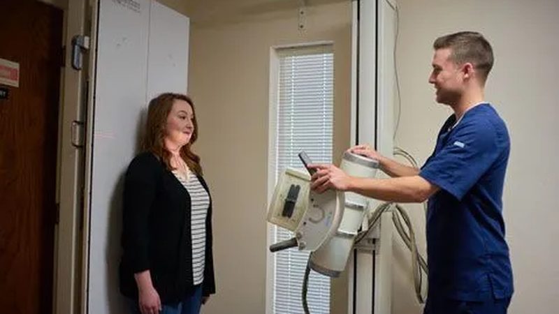 A staff member operating a digital X-ray unit with a patient